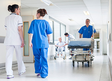 Présentation d'un hôpital avec plusieurs infirmières et brancardier qui traversent les couloirs